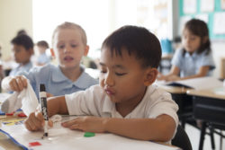 Children marking lines on paper and working with arts and crafts