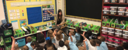 A teacher points to a monthly calendar she has prepared for the class